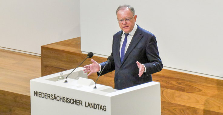 Ministerpräsident Stephan Weil steht gestikulierend hinter einem Rednerpult, das die Inschrift "Niedersächsischer Landtag" trägt.