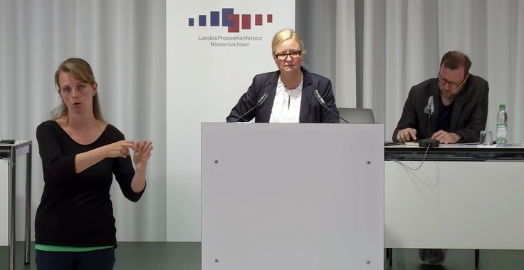 Claudia Schröder in der Pressekonferenz des Corona-Krisenstabs mit einer Gebärdendolmetscherin neben sich.