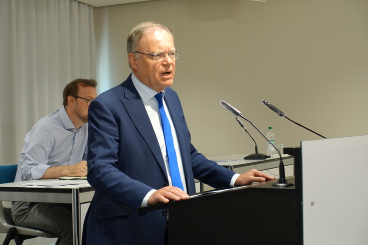 Ministerpräsident Stephan Weil steht an einem Podium und spricht.