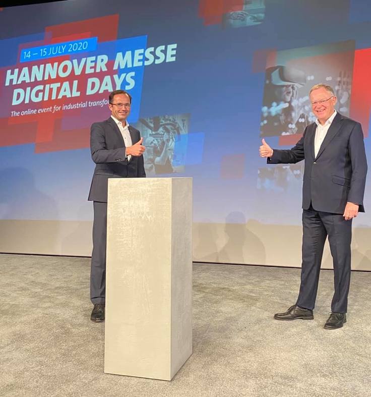 Ministerpräsident Stephan Weil und ein Vertreter der Hannover Messe zeigen den Daumen nach oben, hinter ihnen ist Werbung für die Hannover Messe Digital Days zu sehen.