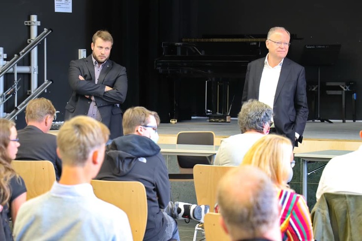 Ministerpräsident Stephan Weil steht mit einem Lehrer vor sitzenden Schülerinnen und Schülern des Schulzentrums Wedemark.