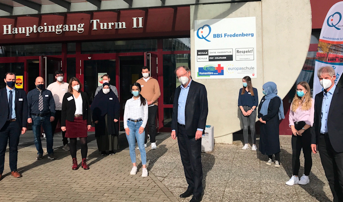 Ministerpräsident Stephan Weil steht mit Schüler und Lehrern vorm Eingang der BBS Fredenberg in Salzgitter. Alle tragen Mund-Nasen-Schutze und halten Abstand zueinander.