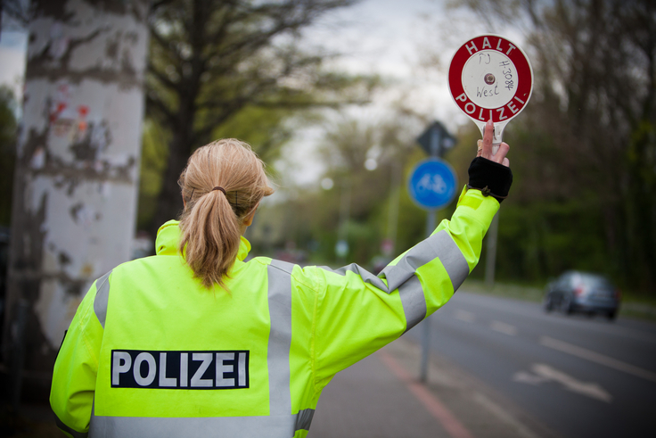 Eine Polizistin winkt Verkehrsteilnehmende aus dem Verkehr.