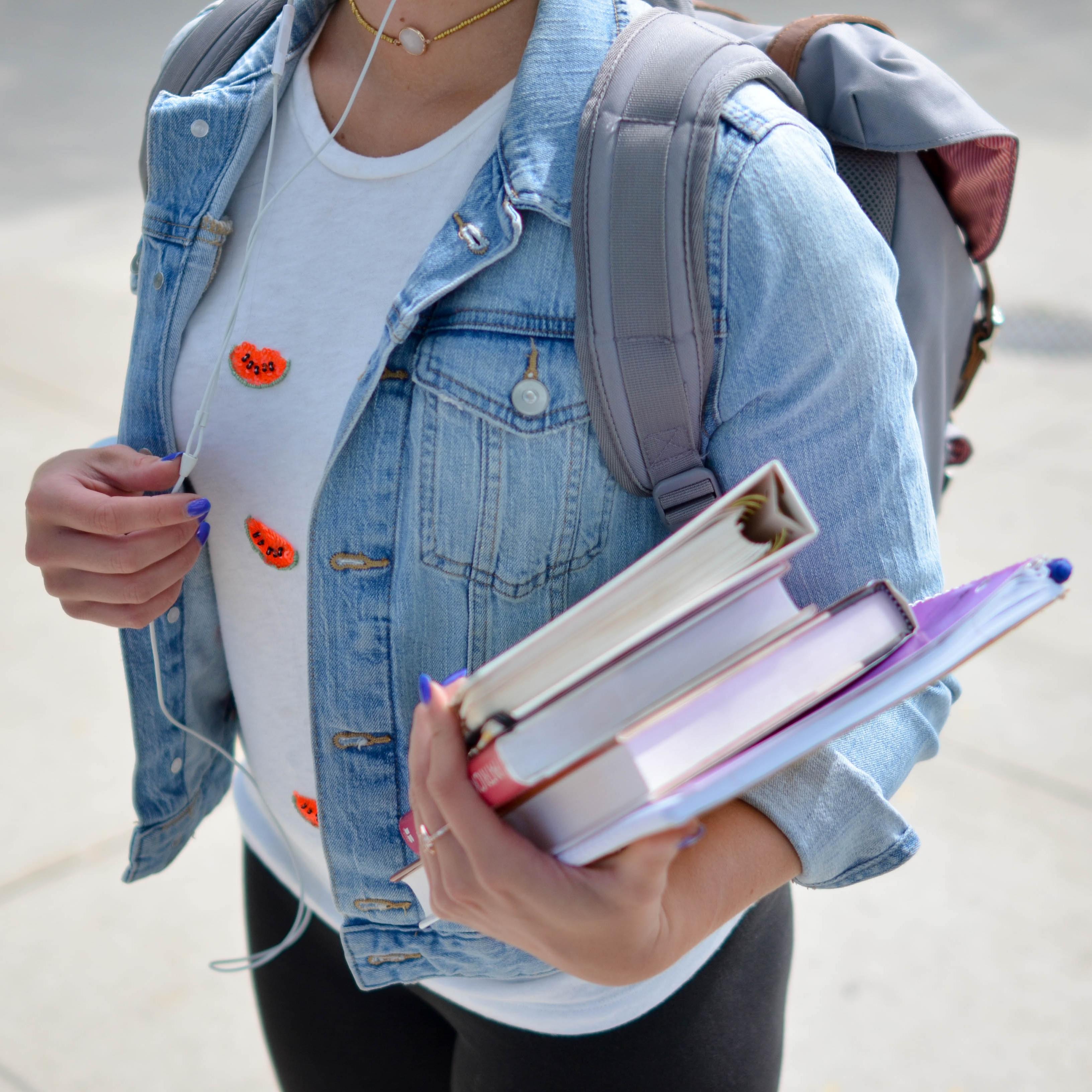 Symbolbild: Schülerin mit Rucksack und Büchern im Arm.